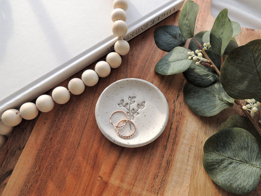 beige speckle ring dish with leafy design in center