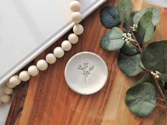 beige speckle ring dish with leafy design in center